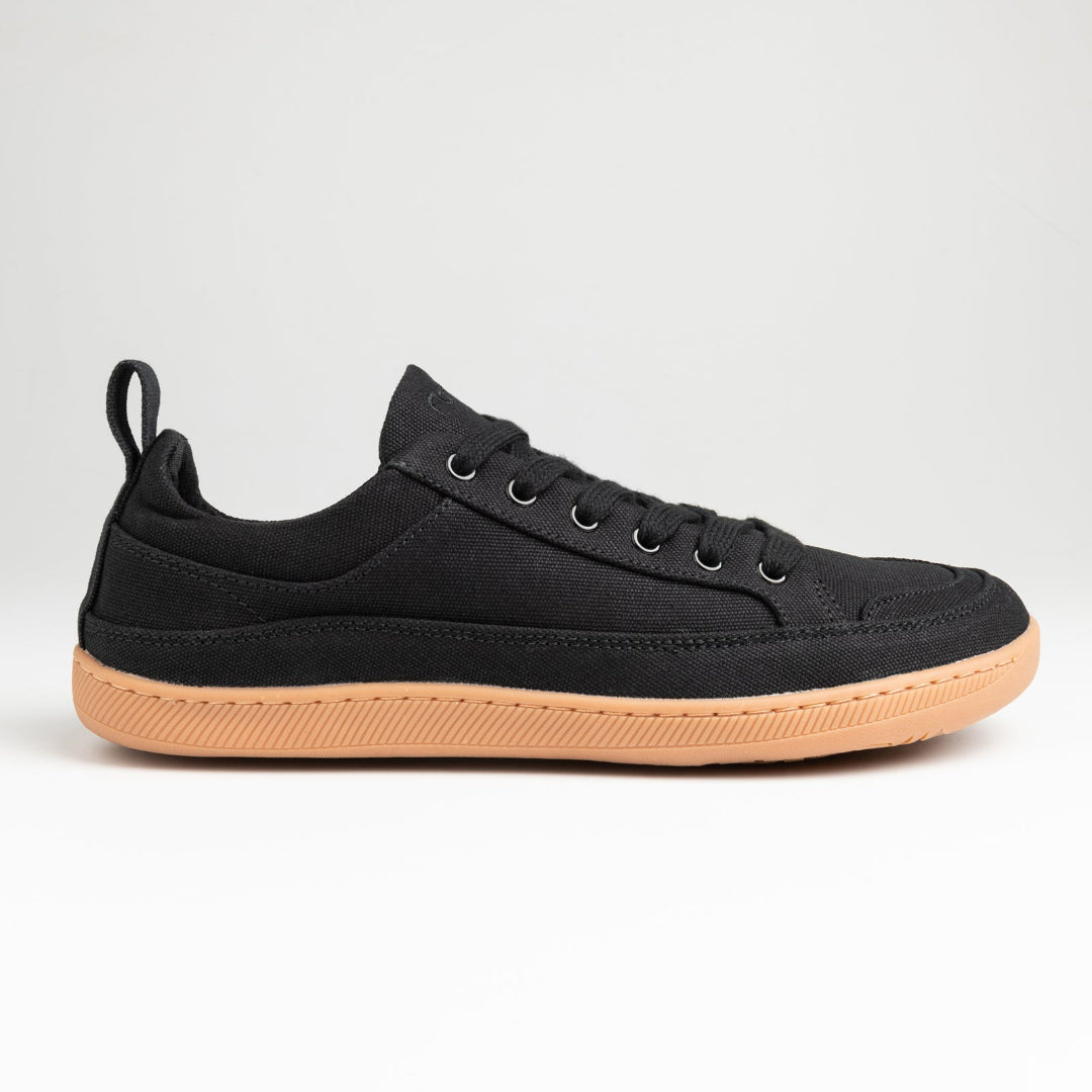 Black barefoot sneaker with a tan sole on a light gray background